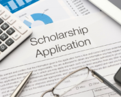 Paper labeled Scholarship Application with a calculator and glasses laying on it